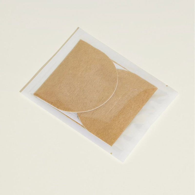 שני רפידות חצי עיגוליות בצבע חום בהיר, בתוך אריזה שקופה על רקע בהיר.