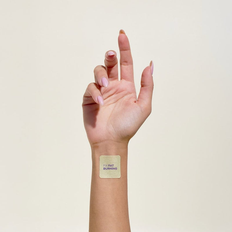 יד מורמת עם מדבקה מרובעת על פרק כף היד, עליה כתוב "FIX FAT BURNING".