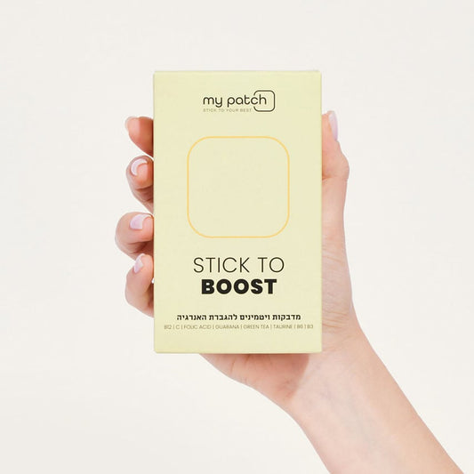 יד אוחזת בקופסה צהבהבה של מדבקות ויטמינים "Stick to Boost" להגברת האנרגיה.