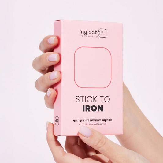 יד מחזיקה קופסה ורודה של מדבקות ויטמינים לחיזוק הגוף, עם הכיתוב "STICK TO IRON".