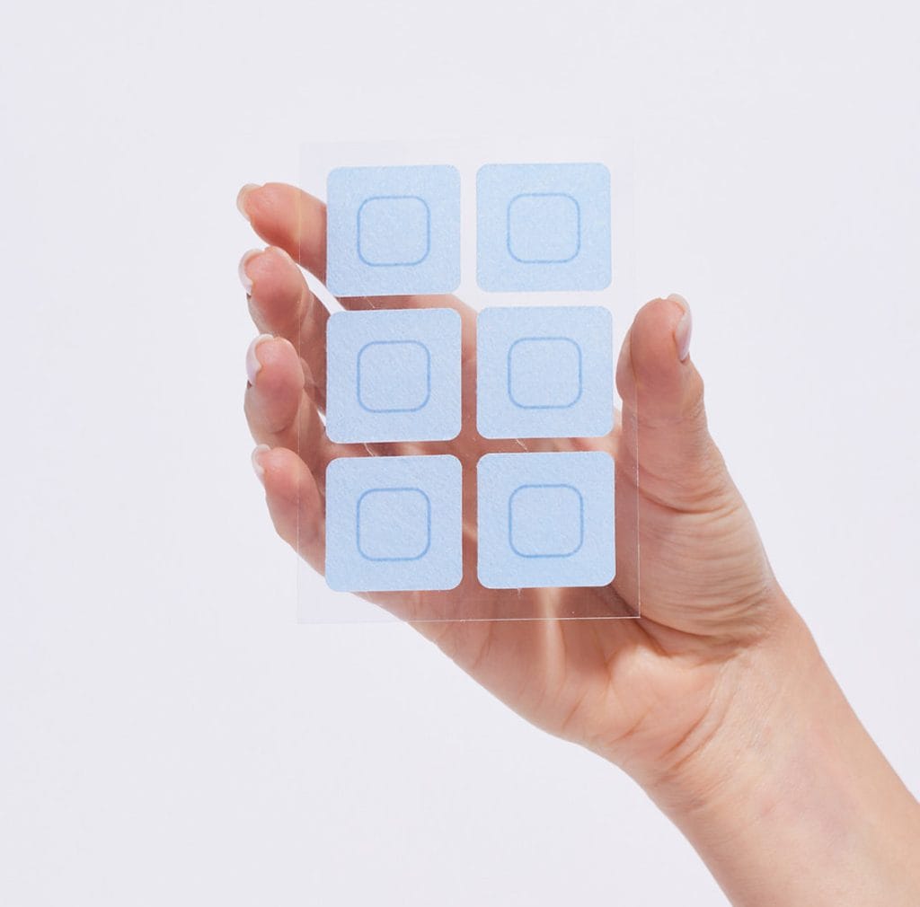 יד מחזיקה דף פלסטיק שקוף עם שישה ריבועים כחולים בהירים ועליהם ריבועים כחולים כהים יותר.