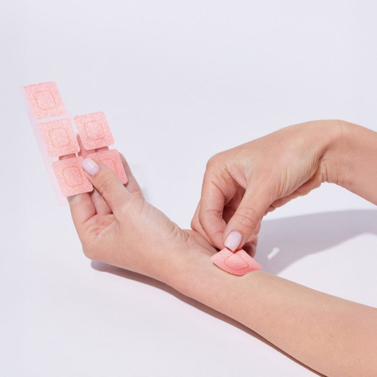 יד מדביקה מדבקה ורודה קטנה על היד השנייה, מתוך דף מדבקות.